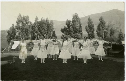 [Freshman girls, dressed in white and wearing garlands, performing 'Flower Dance' at the annual Athl