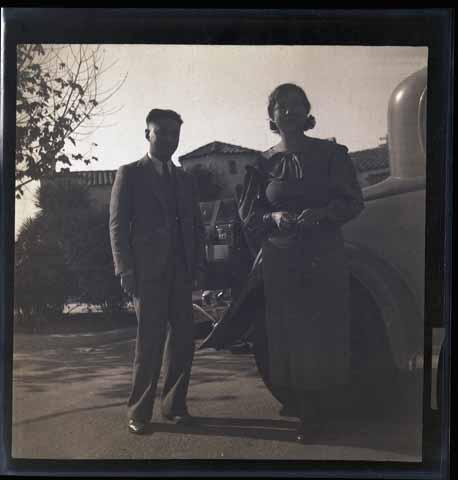[Man and woman next to car with luggage]